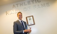 Chris Tamas with his award in front of the new Athletic Hall of Fame