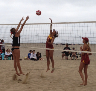 USC player tries to hit over the block of a SBCC club player during women's team sand volleyball match at East Beach.