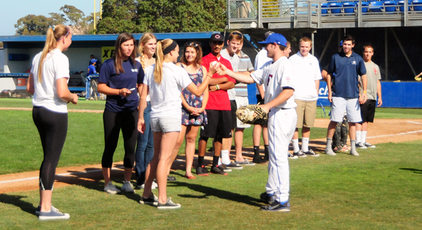 Dos Pueblos softball player Maddie Buie is handed a ball from a Foresters player to throw out the ceremonial first pitch at last year's Presidio Game Day.